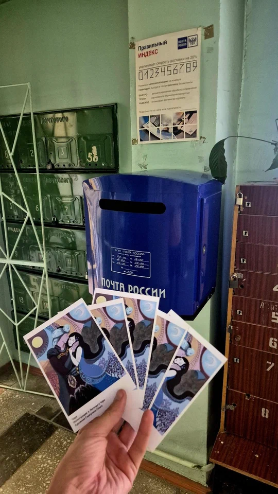Открытки в руке возле почтового ящика